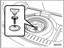 16. Store the flat tire in the spare tire compartment. Put in the spacer and tighten the attaching bolt firmly.